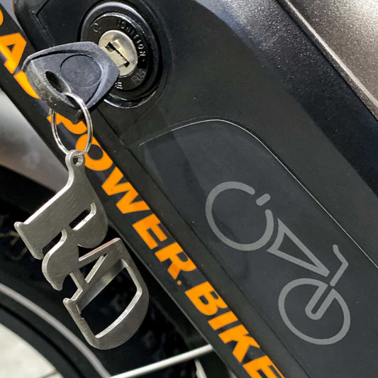 rad power bikes bottle opener keychain hanging from battery on bike